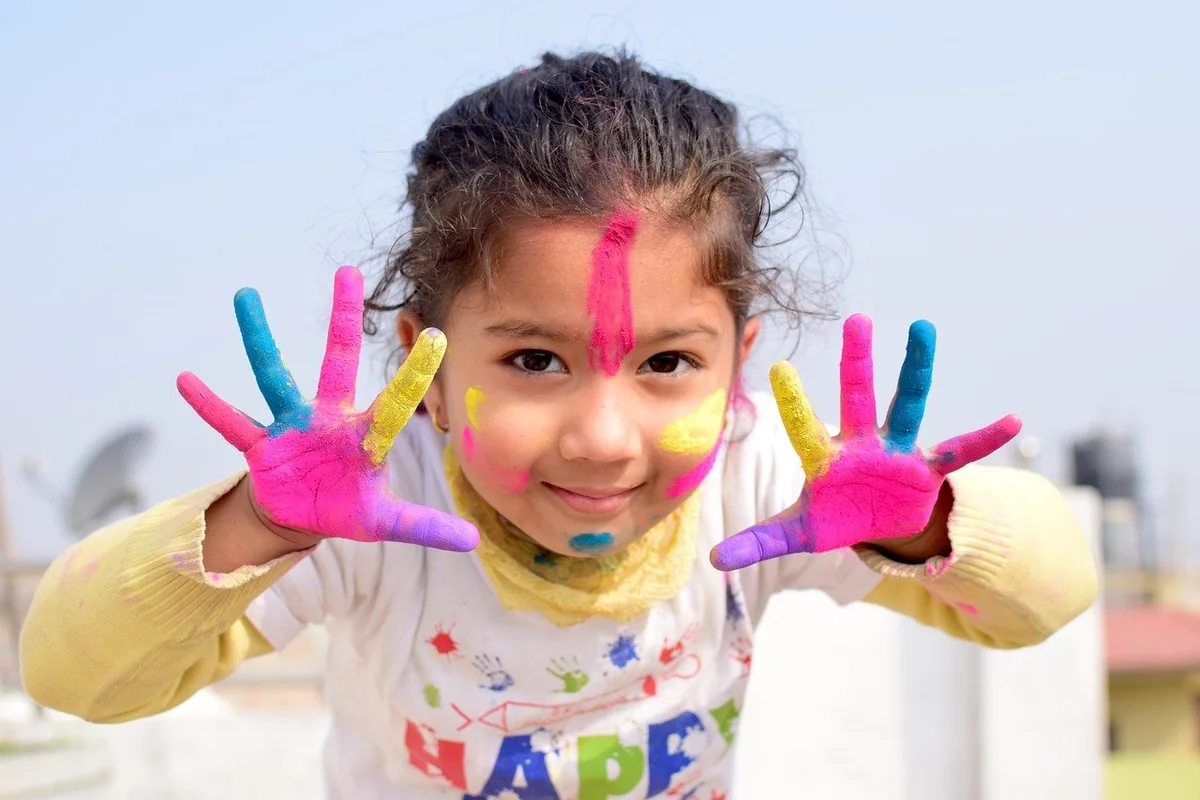 Niña mostrando las manos cubiertas de pintura de colores.