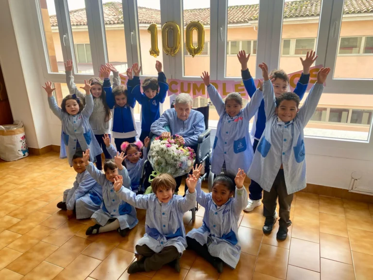 Alumnado de Infantil levantando los brazos junto a sor Enriqueta en su 100.º cumpleaños