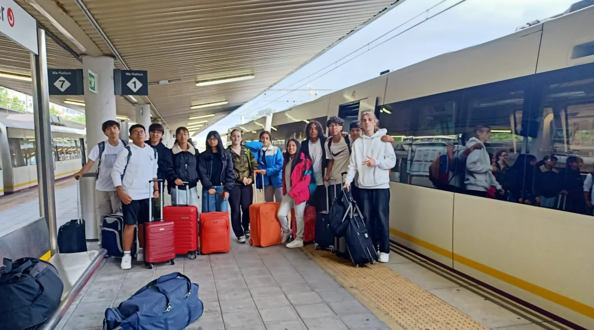 Grupo con maletas posando en un andén junto a un tren.